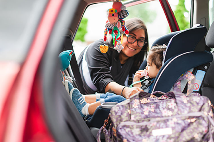 A loving mother buckles her daughter into the car seat for safety while driving. Shot in Vancouver Washington