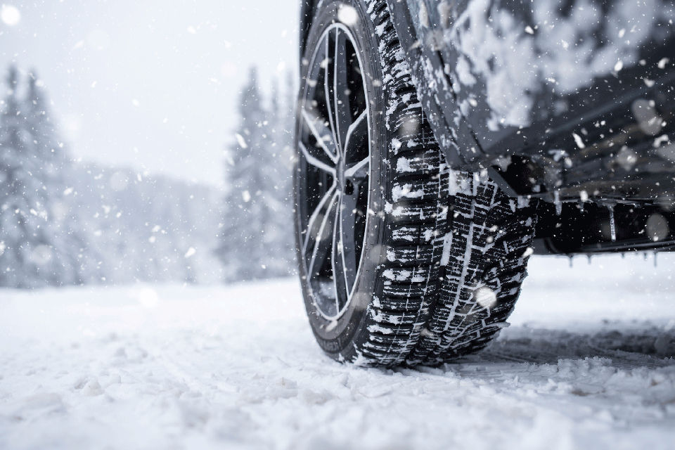 Close-up low angle shot of car tire on a snowy road in winter.