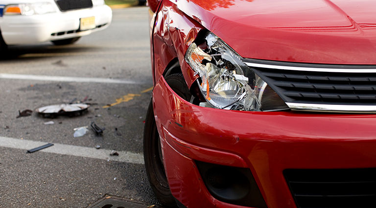Red car with front-end damage, reflecting collision or liability insurance coverage