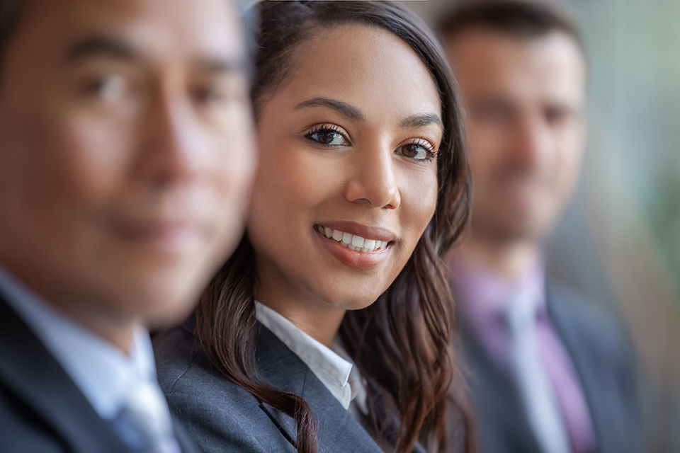 Portrait of young multiracial Black businesswoman smiling in meeting with colleagues in a row
