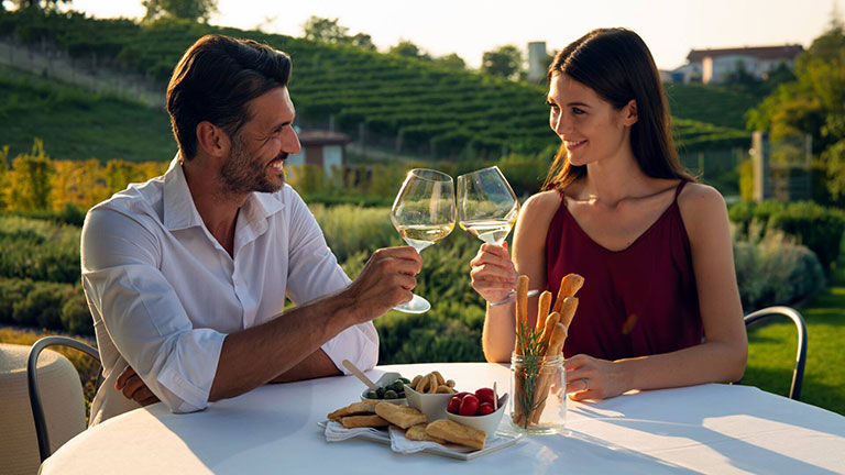 Couple toasting, with lush greenery in the background