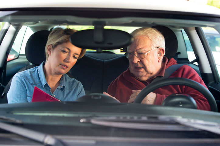 Senior man in a car with driving instructor taking lessons