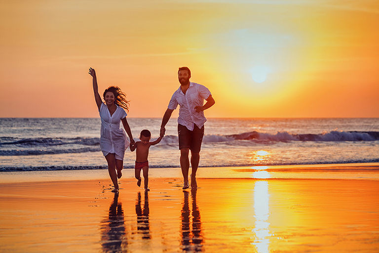 Delta Vacations, family with a samll child on the beach at sunset.