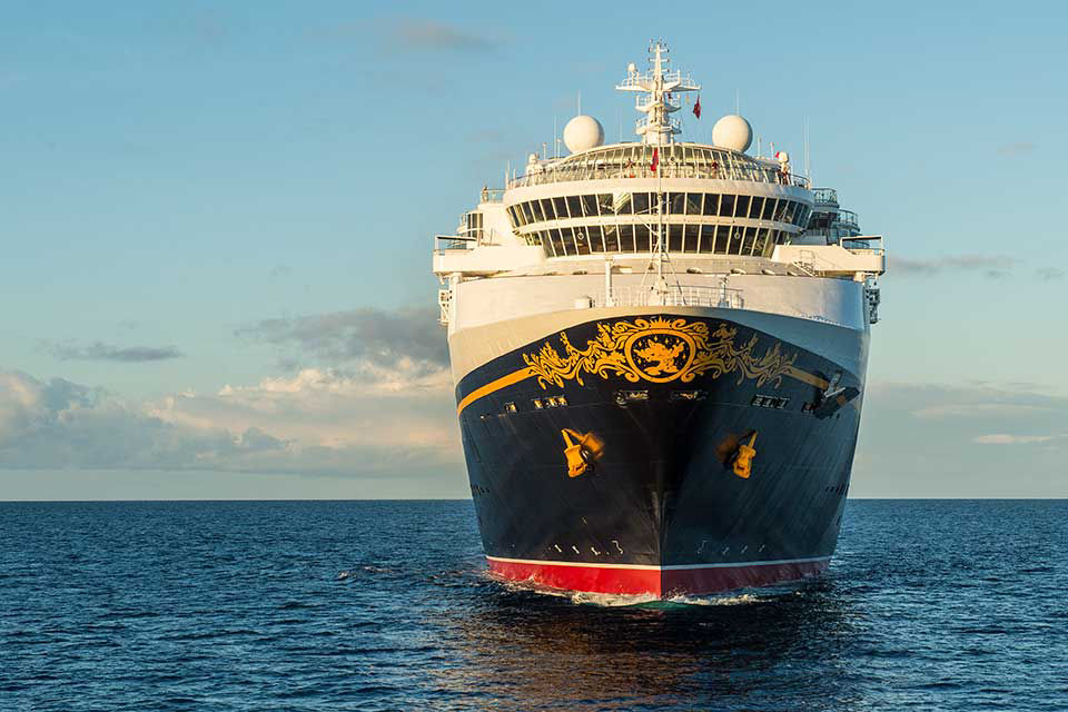 Disney cruise ship sailing the waters at sunset.