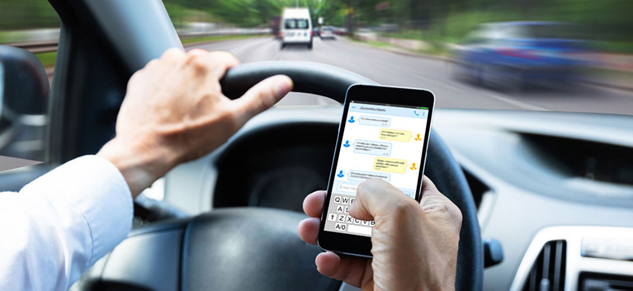 A man driving while texting on his smartphone.
