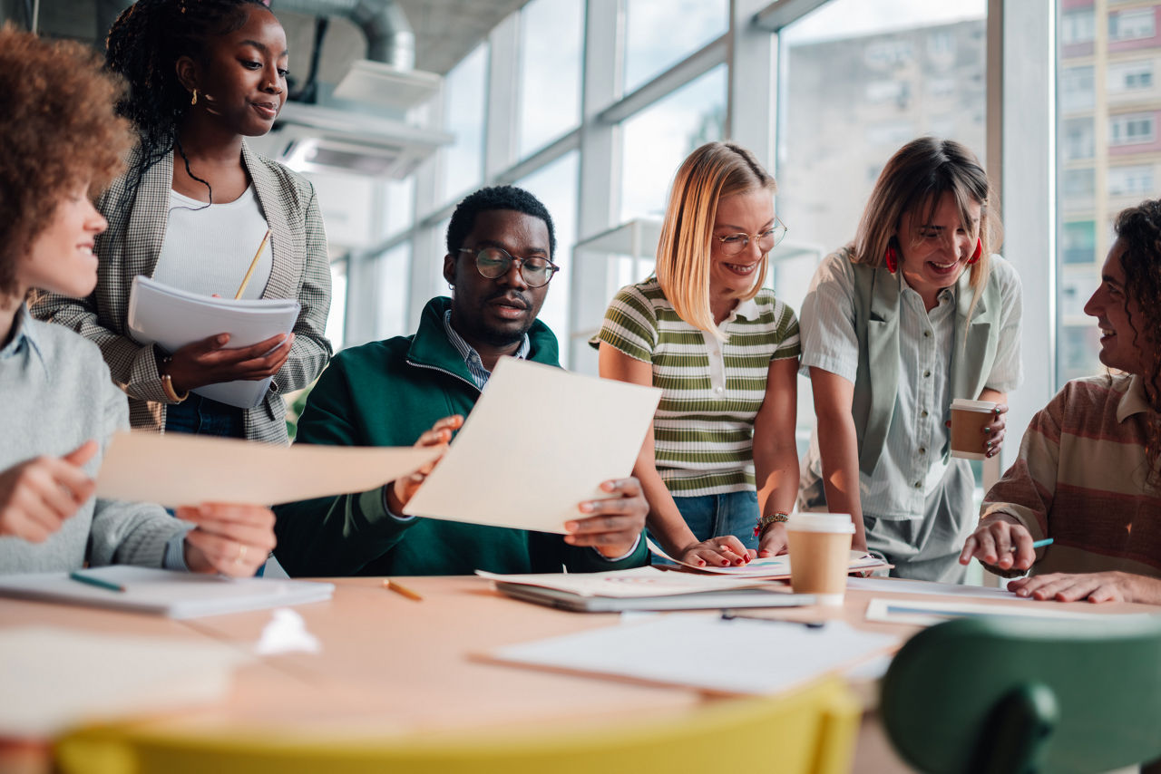 Group of young adult and mid adult mixed age range people working together around a table in a modern office