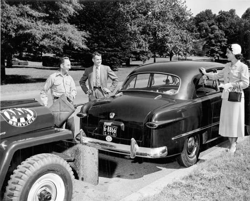 Historical photo of AAA technicians speaking with a member by her vehicle