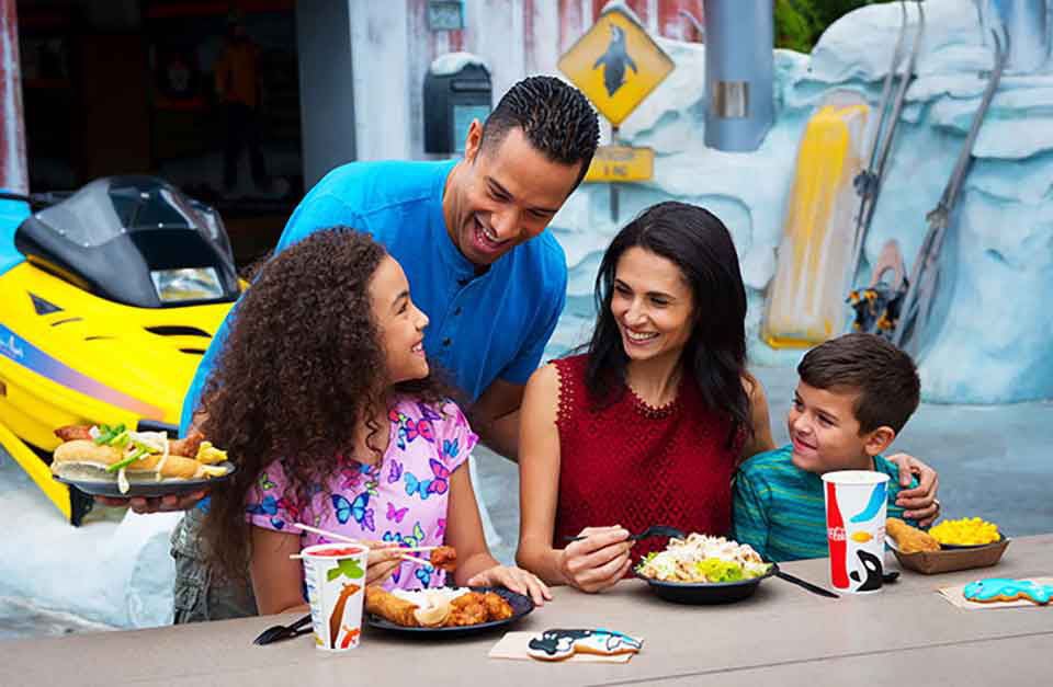 Blended family dines outside at seaworld smiling and sharing a laugh.