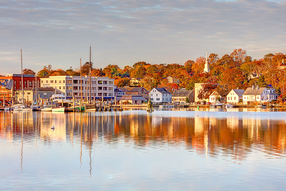 Sun lit coastal waterfont town in Connecticut with fall leaves.