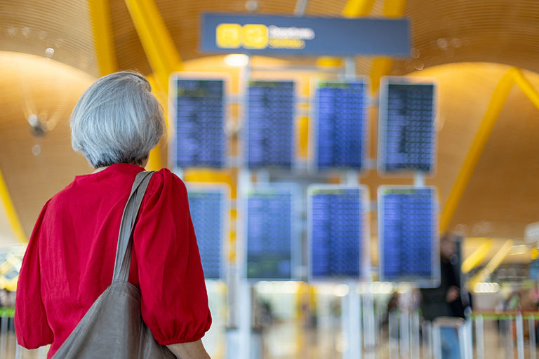 Senior woman looking at timetable board while waiting her flight departure at the airport.