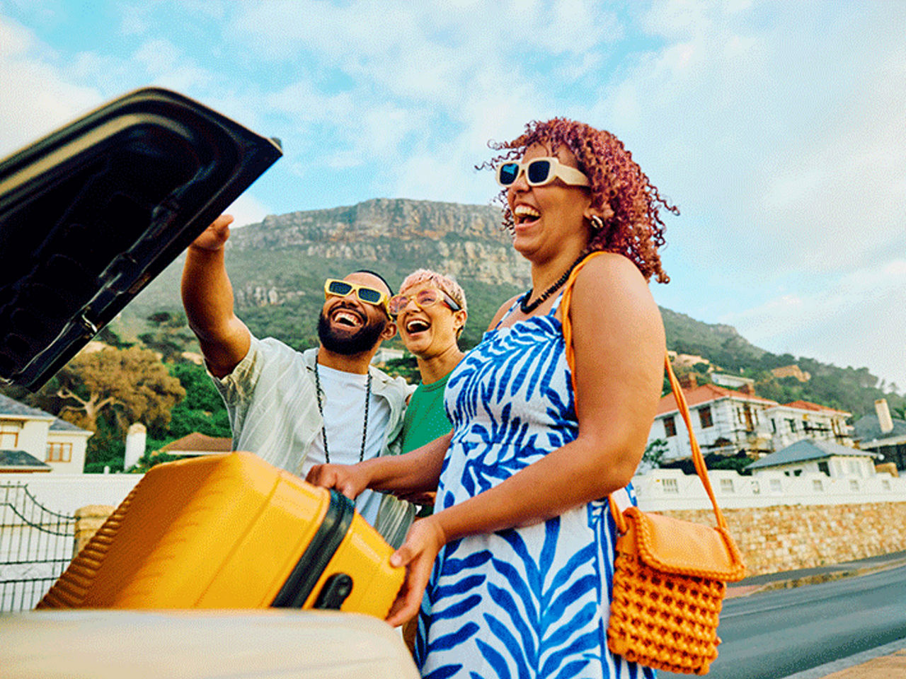 Friends unloading suitcases from car.