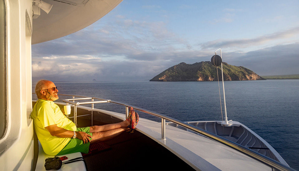 Smiling mature man, enjoying the sunset on the ship deck.