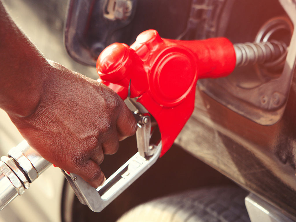 Detail of persons hand filling up the tank with nozzle in Africa