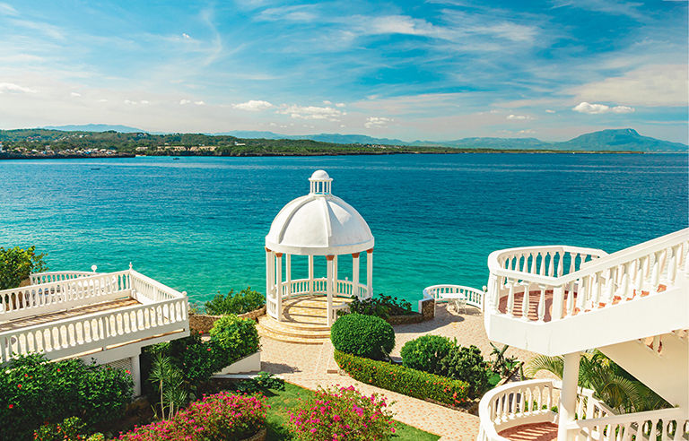Beautiful white gazebo and tropical flower garden on Caribbean ocean background, summer mountain view , Sosua, Puerto Plata, Dominican Republic