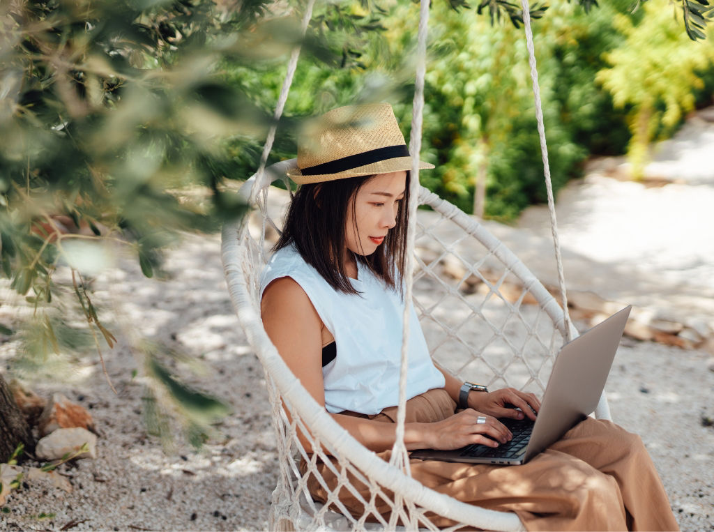 woman sitting on laptop at the beach