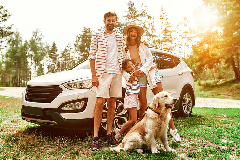 The whole family came to nature for the weekend. Mom and Dad with their daughter and a Labrador dog are standing near the car. 