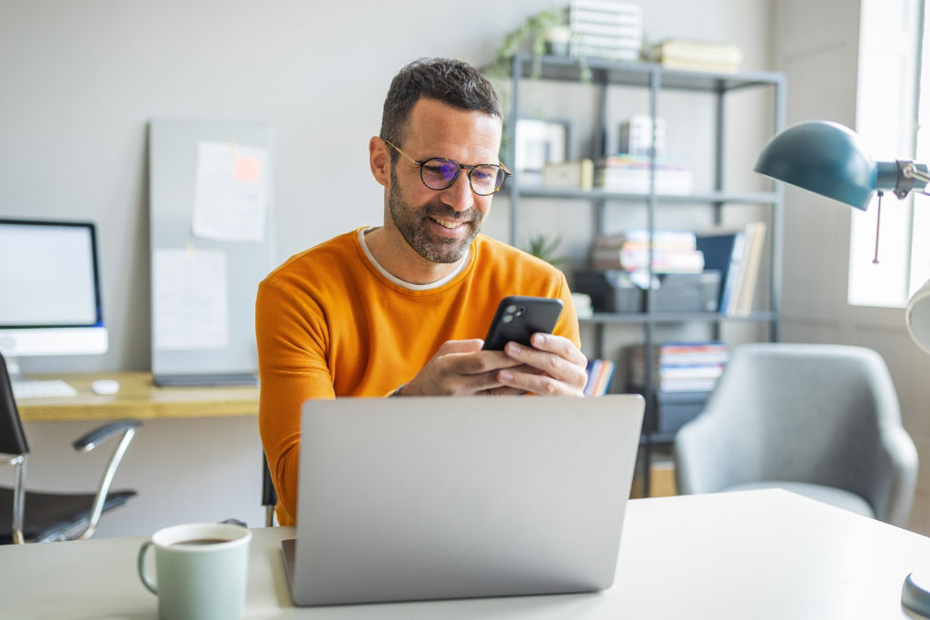 Man looking at his cell phone sitting at a desk