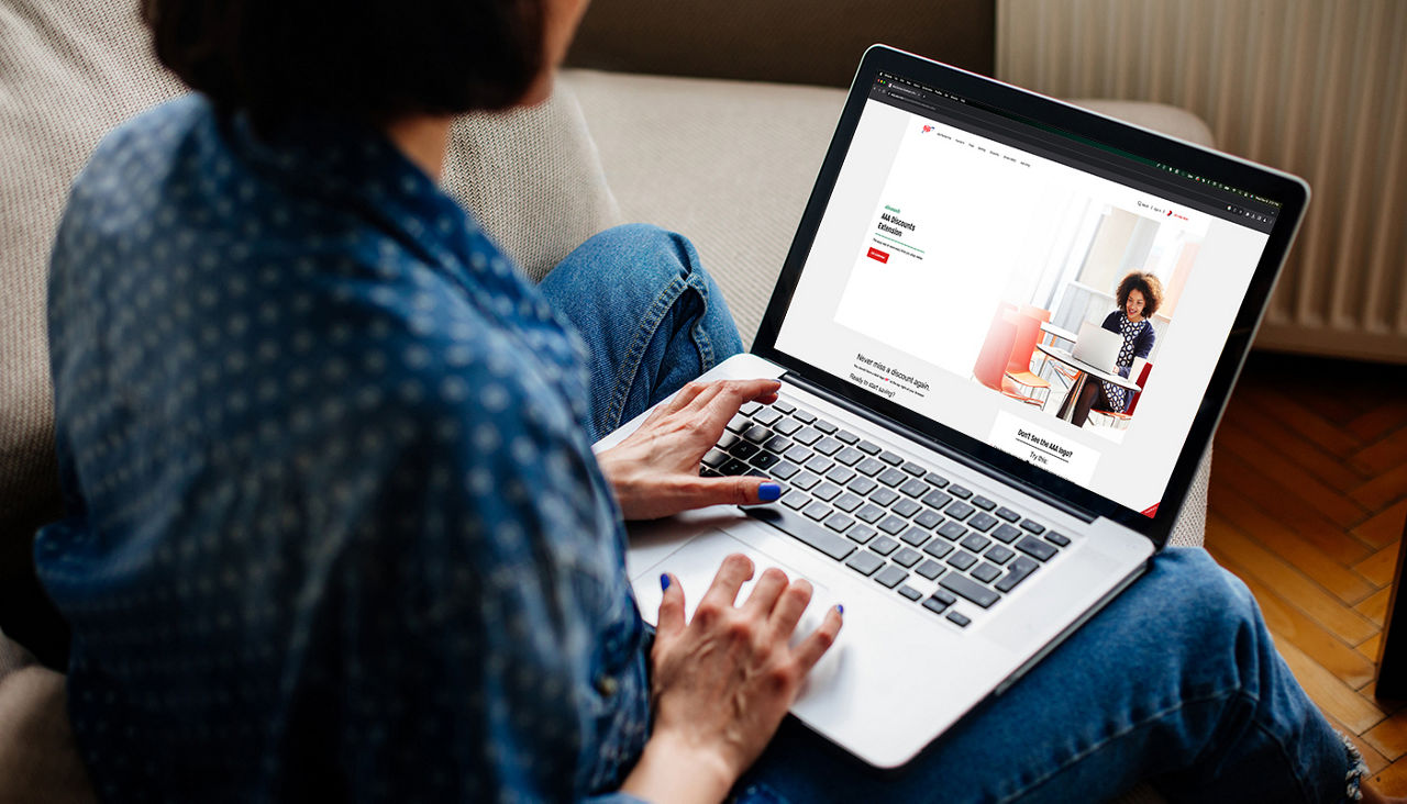 Woman sitting on a sofa researching AAA Dollars Online Mall on her laptop