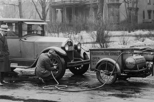 Historical photo of roadside assistance provider fixing a flat tire