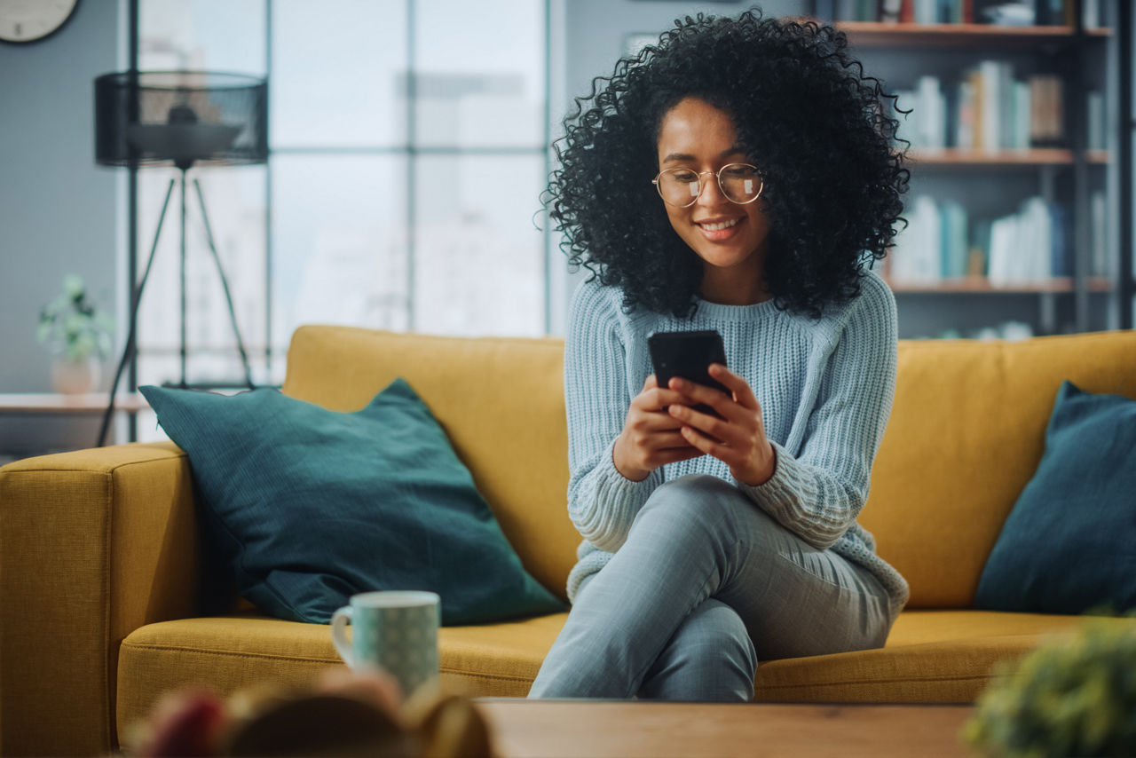 Young woman sitting on sofa looking at her phone. 