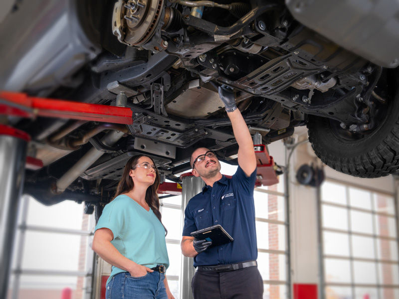 Car Care mechanic with customer under the carriage of a car