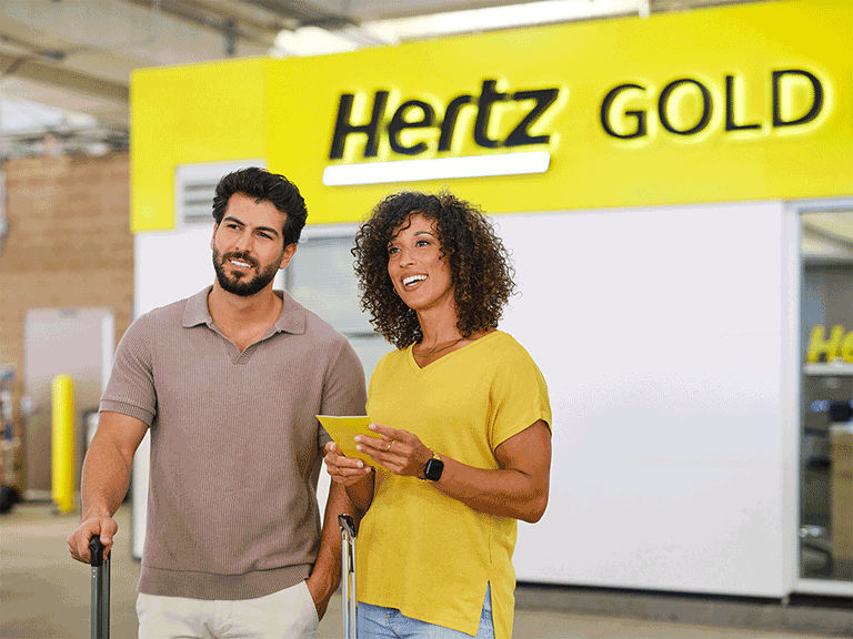 AAA Hertz Gold Members walking to rental with luggage