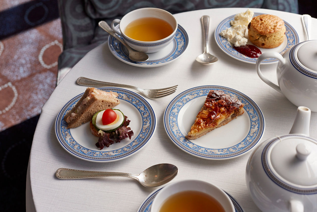 Small bites and teacups with tea on a fancily set table for high tea 