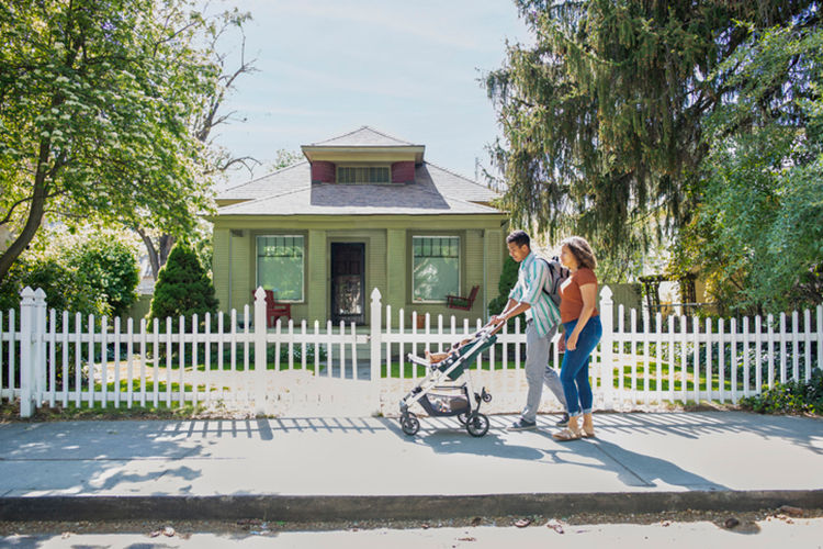 Couple pushing stroller in a sunny neighborhood.
