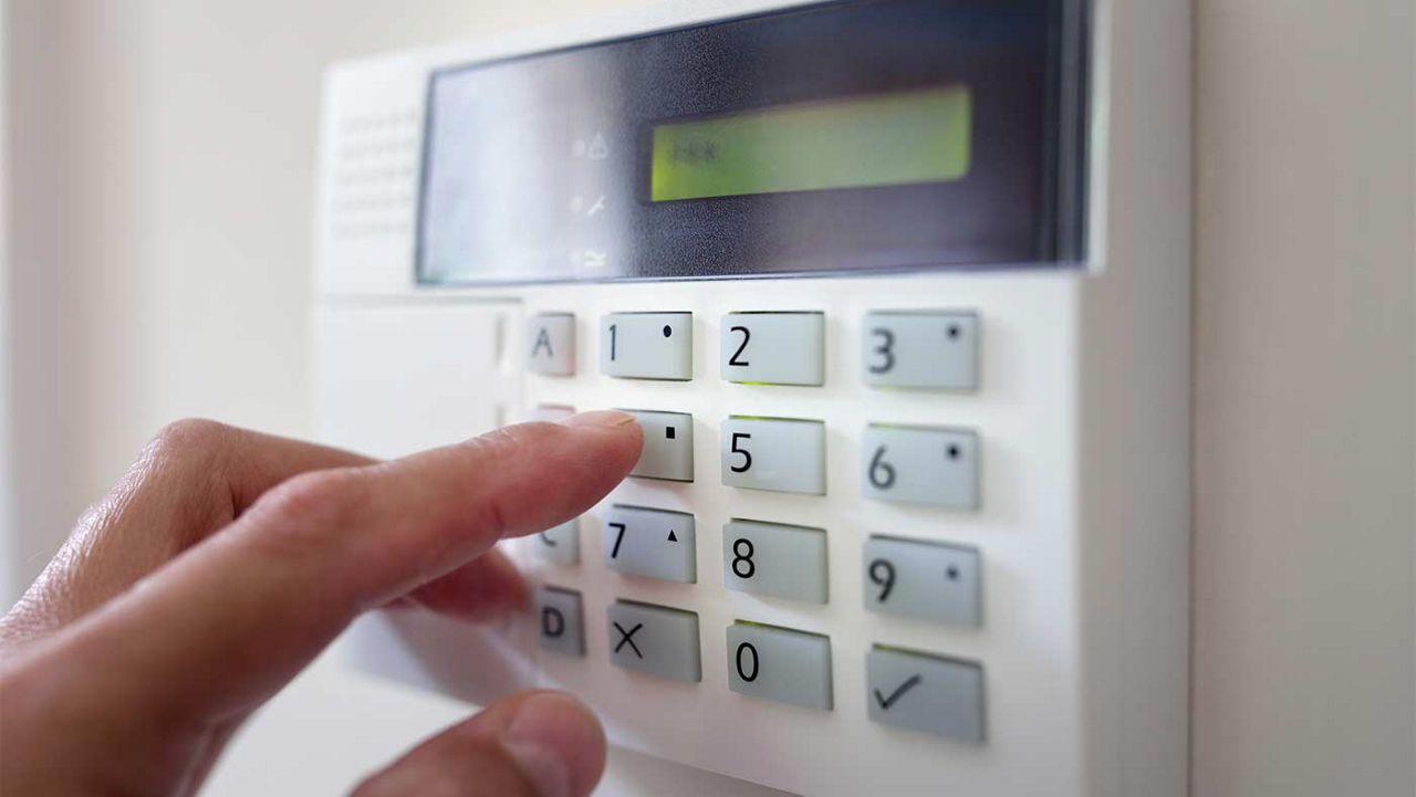 A close-up view of someone punching a code into a home alarm system.