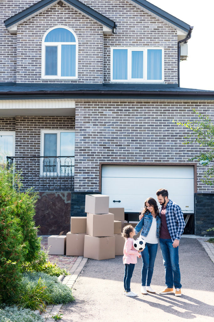 Young family standing together in front of new house.