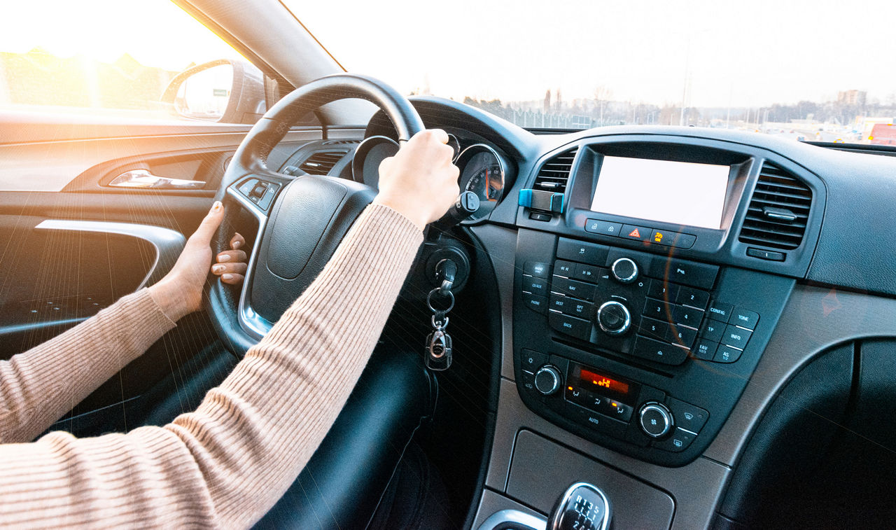 Happy young woman inside vehicle driving in sunny day