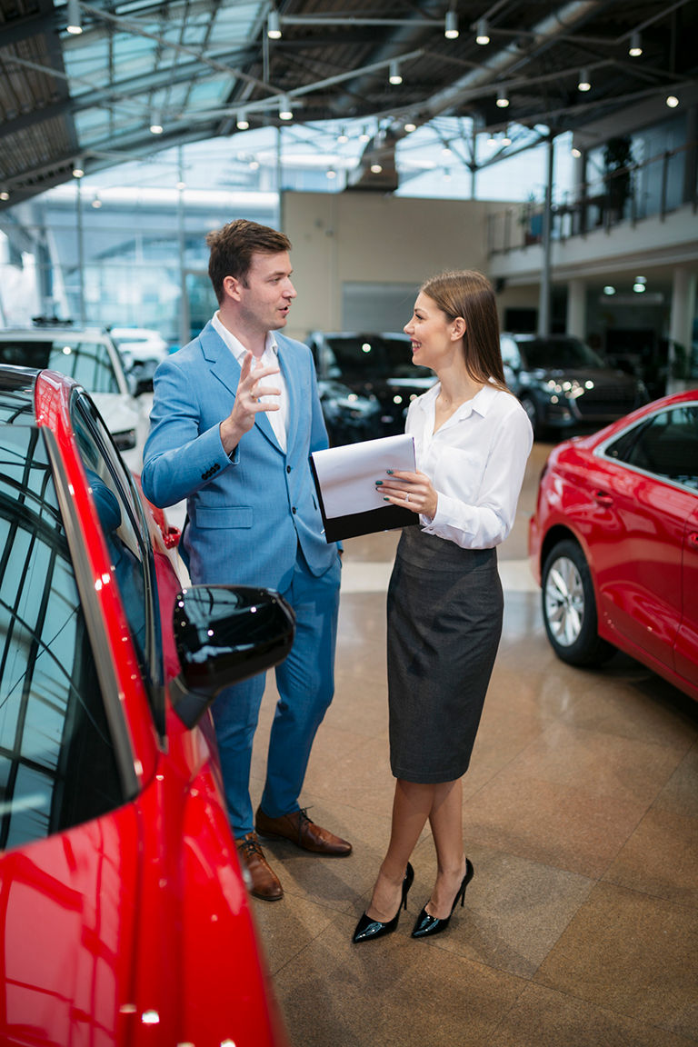 Man in woman beside car, reviewing gap insurance paperwork 