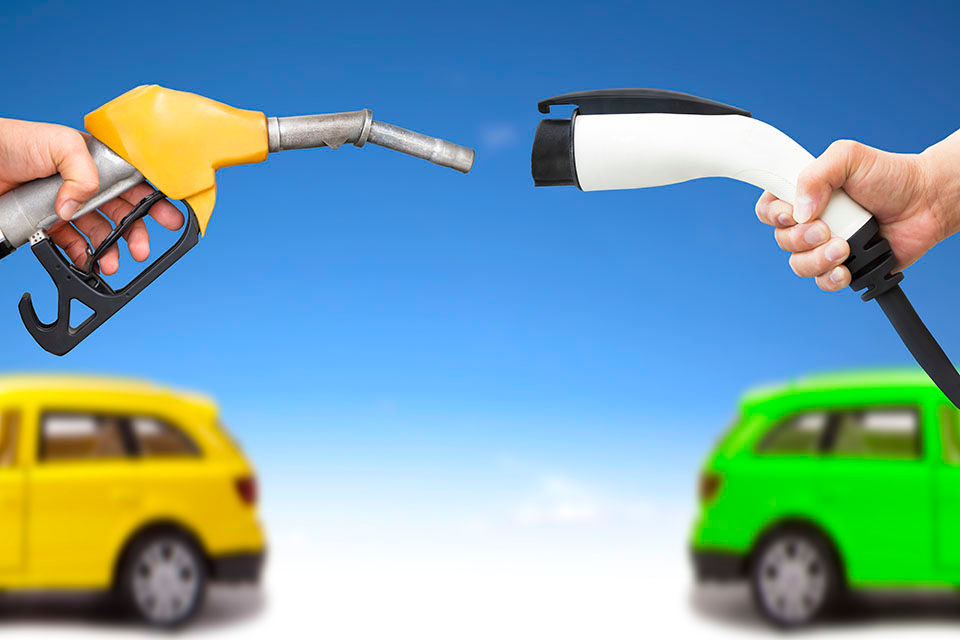 Electric car and gasoline car concept. hand holding gas pump and power connector for refuel.