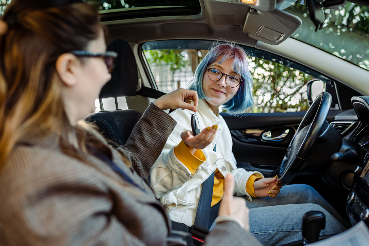 Young woman are given keys inside a car