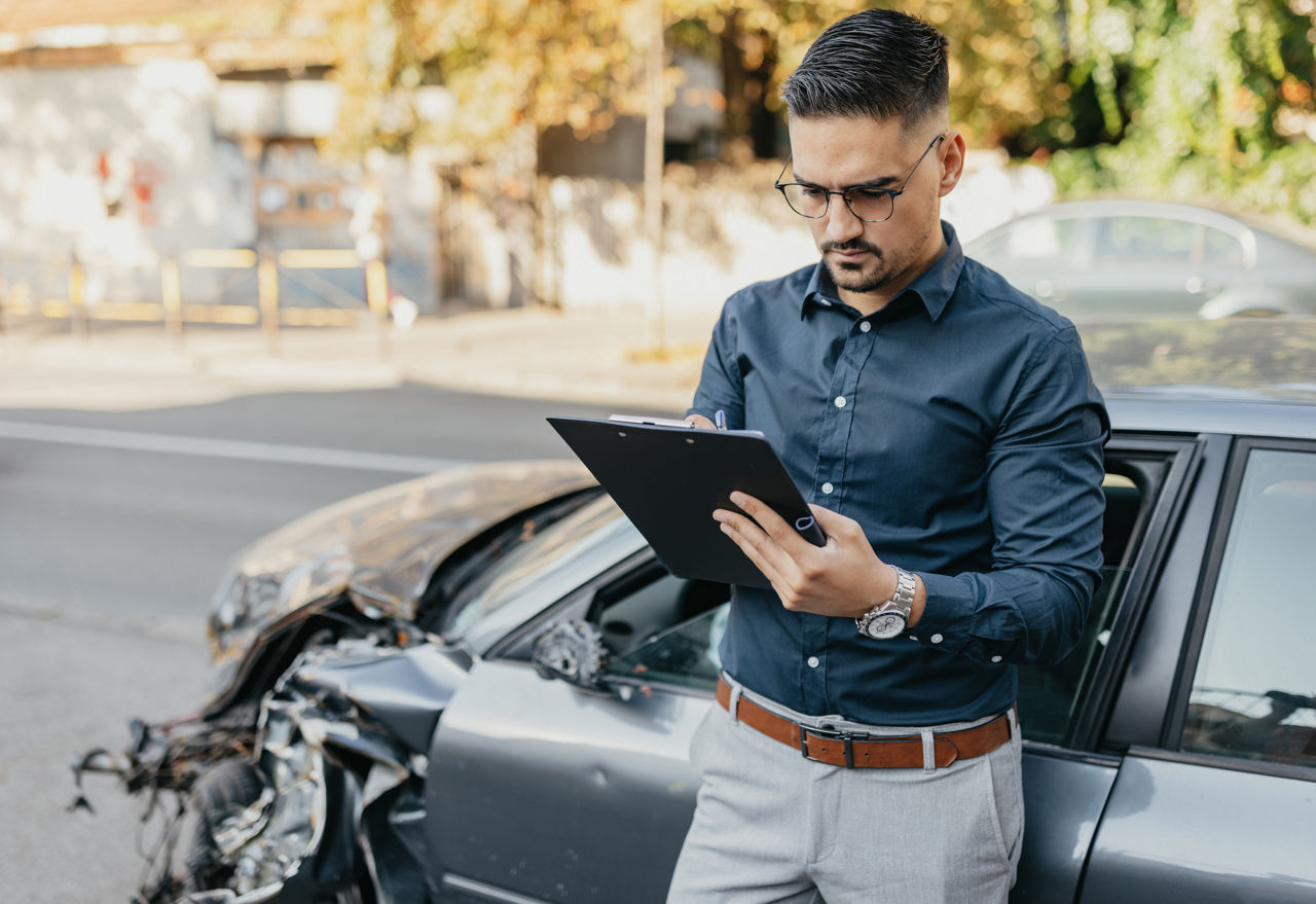 Man by an accident filling out on a clipboard