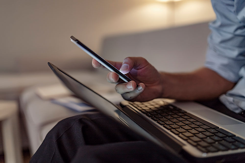 Man holding phone and has a laptop on his lap.