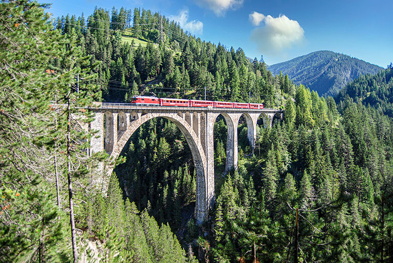 Inspiring Journeys by AAA, Swiss train bridge in the mountains.