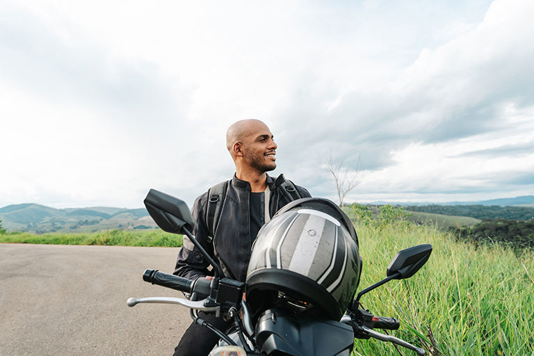 Your man looking at the side while stopped during his motorcycle riding trip.