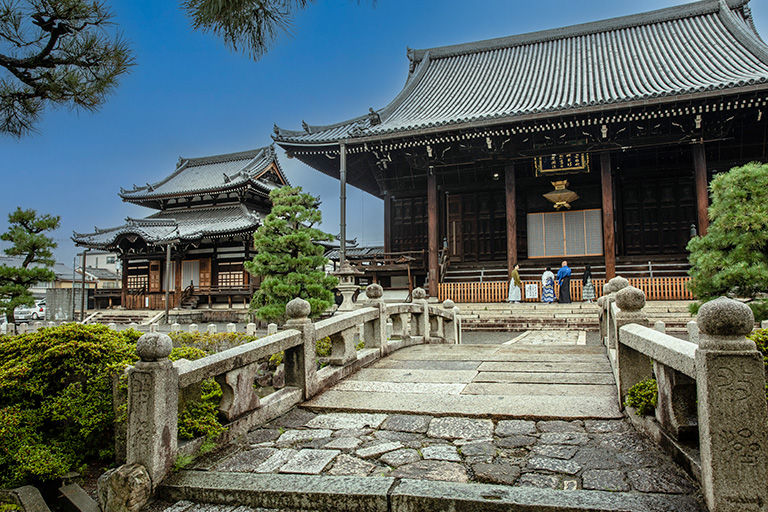 Traditional Japanese temple with ornate roof and stone bridge in foreground