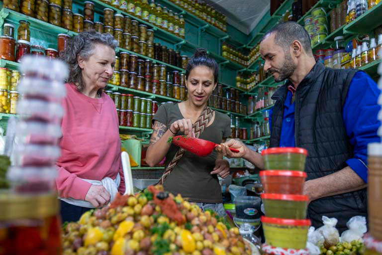 Local vendor showing spices and produce to tourists in traditional market stall