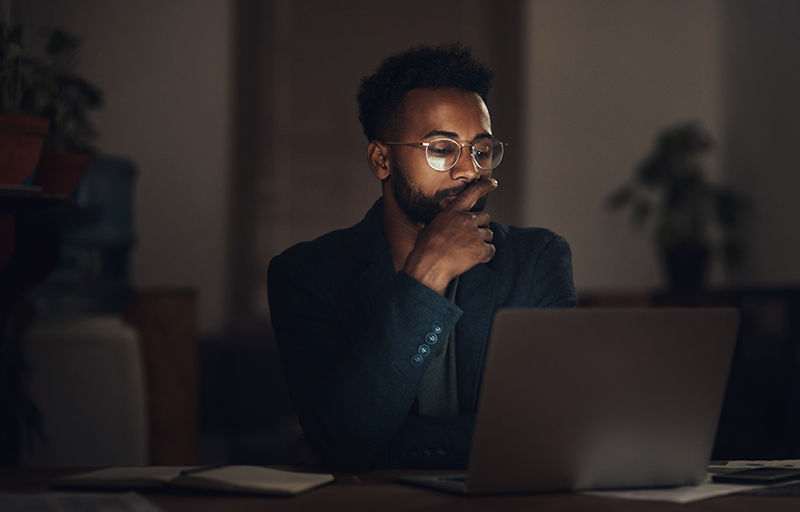 Shot of a young businessman using a laptop during a late night at work