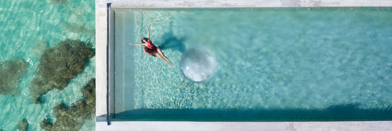 Ariel view of a woman swimming on her back in the La Casa de la Playa infinity pool