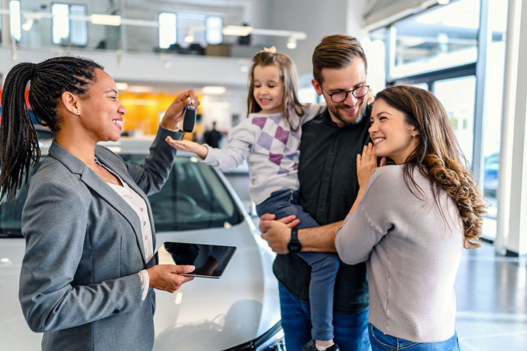 Couple with child receiving keys to new vehicle 