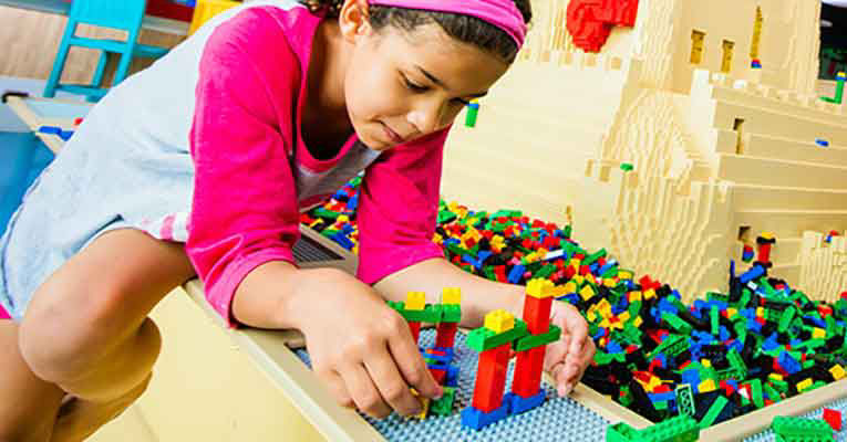 A little girl is piecing together her legos.