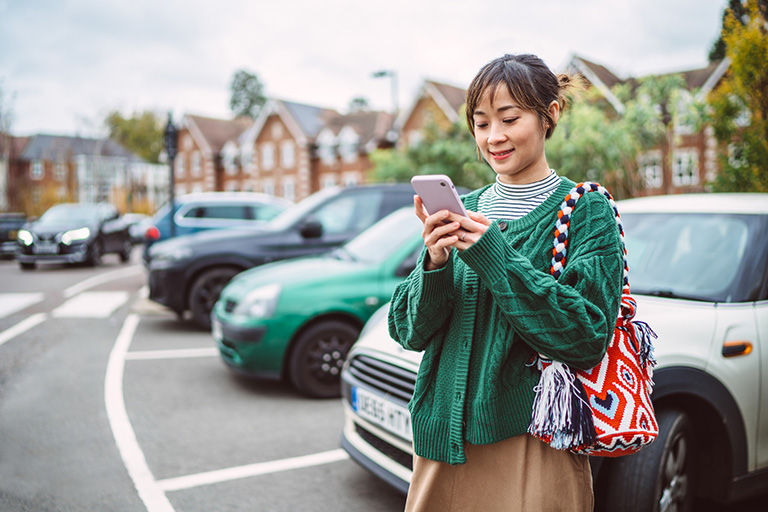A woman uses her phone to reserve a vehicle for a self-guided tour.