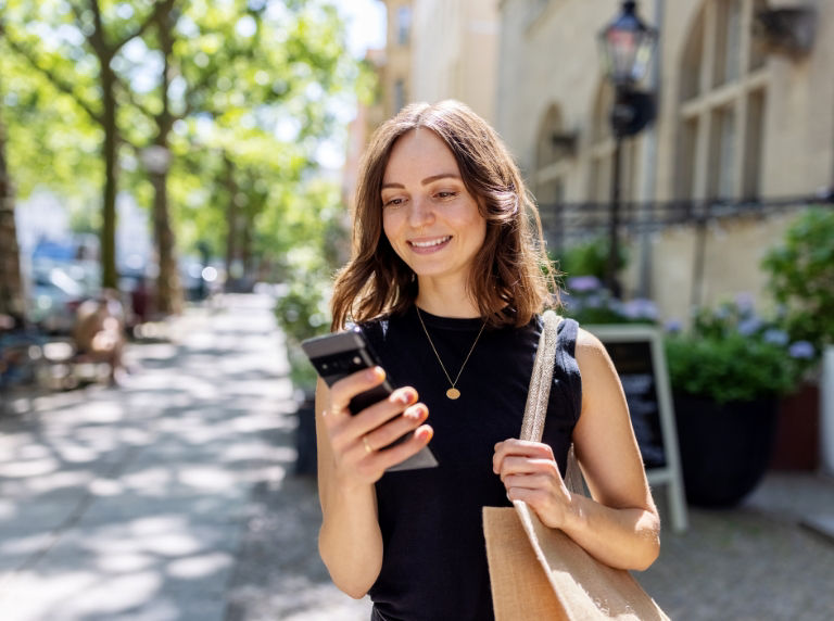 young woman looking at a phone on the sidewalk