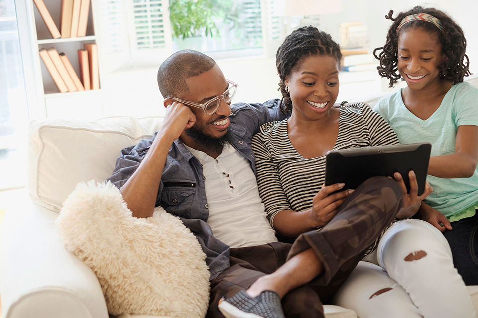 Happy family using digital tablet on sofa.