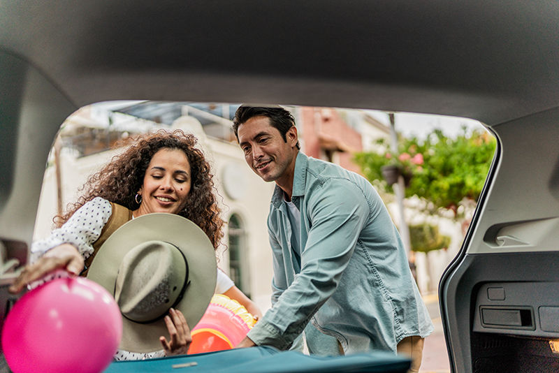Couple unloading luggages from the car trunk