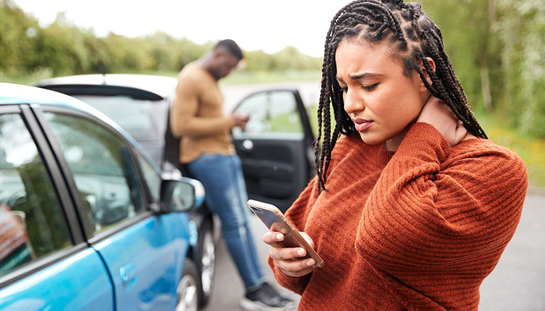 Woman reviewing insurance policy on phone after an accident