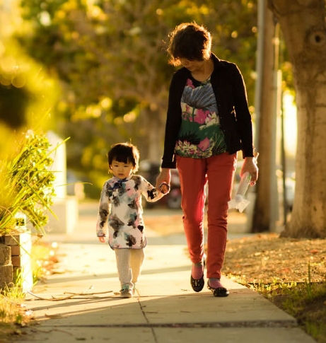 Mom and young daughter walking on sidewalk.